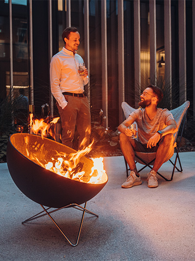 two men sitting around a fire pit.