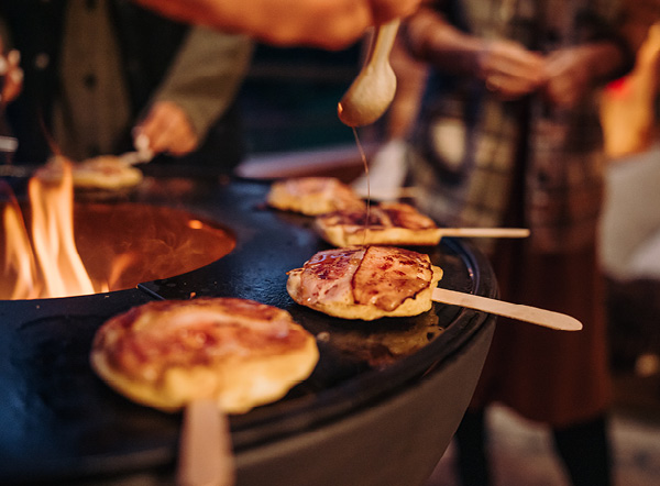 An inviting scene with a person is cooking pizzas on a grill