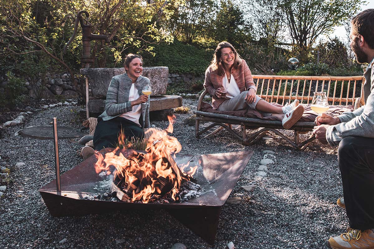 Depicted here is a couple sitting around a fire pit, with the TRIPLE 120 Fire Bowl.