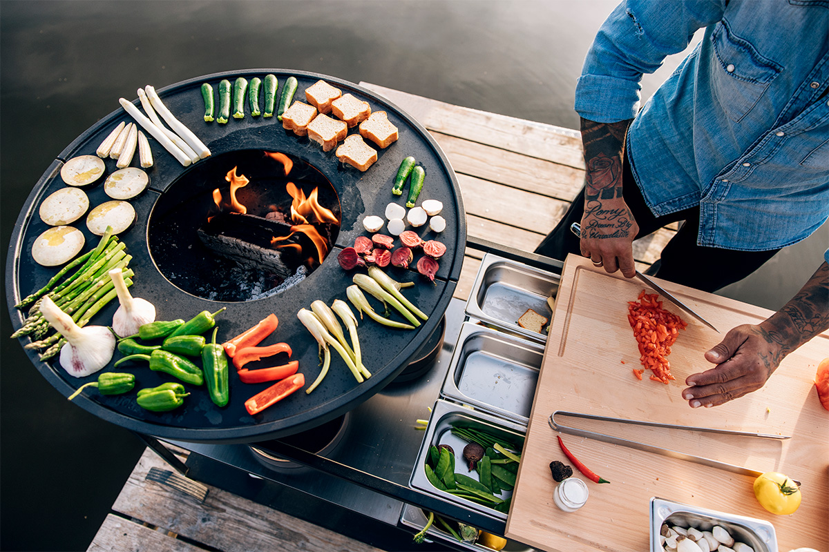 A man preparing food on a grill the 00764 FIRE KITCHEN Stainless Steel Container Set (5 pcs) complements the moment with its thoughtful design.