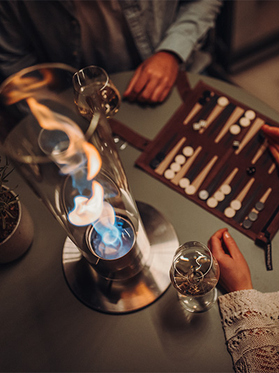 The photo presents a woman sitting at a table, with the LOGO SPIN Table-top fireplace.