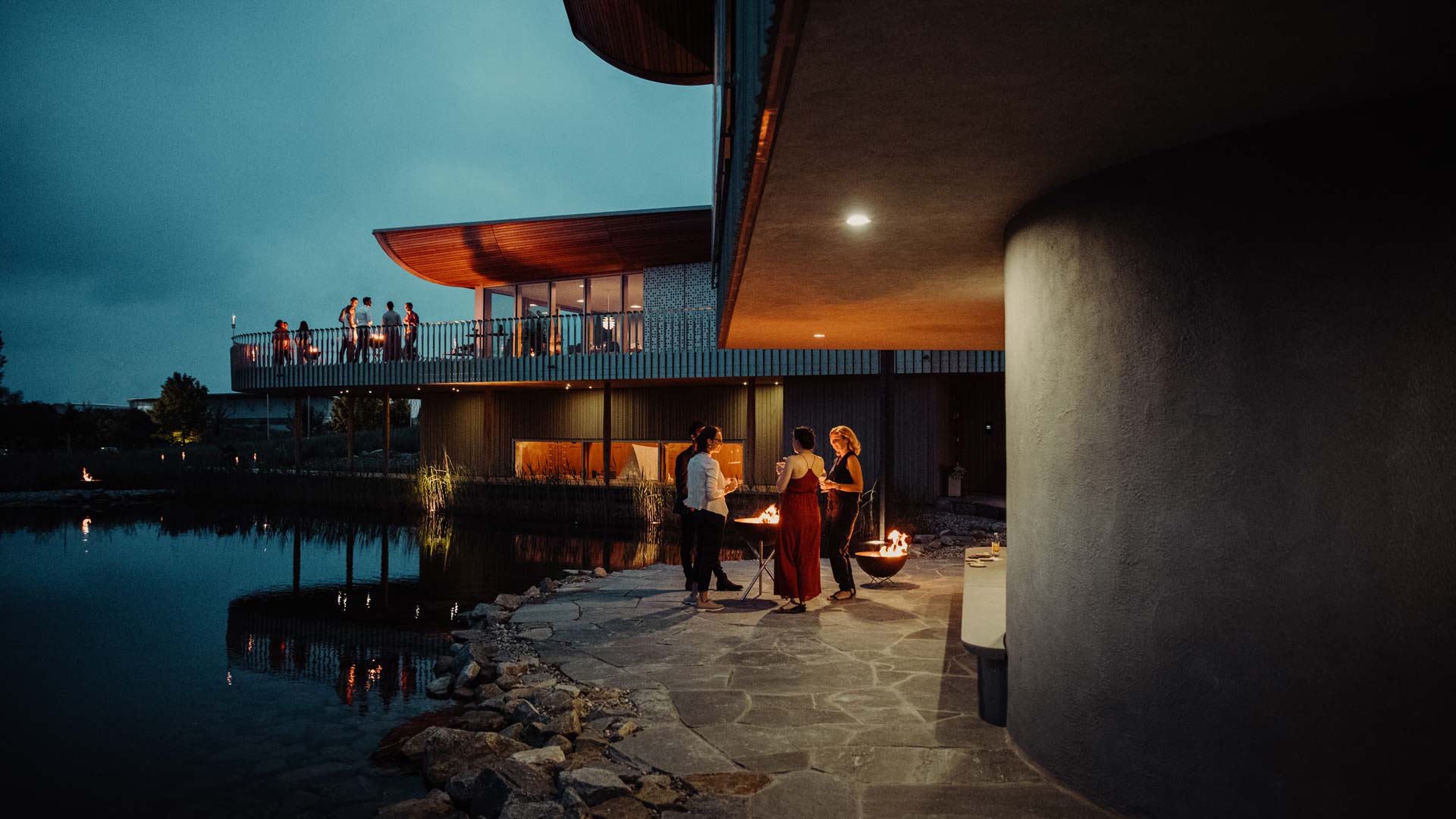 This image shows a couple standing on a patio next to a lake, with the BOWL 70 Cover.