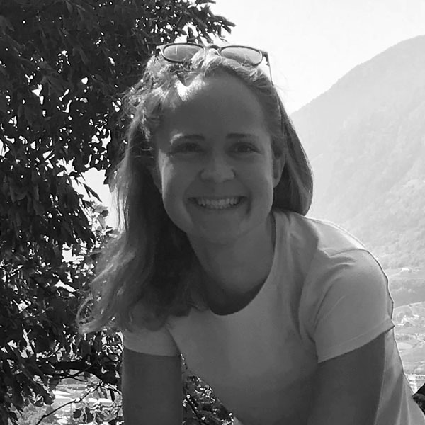a woman sitting on a bench in the mountains.