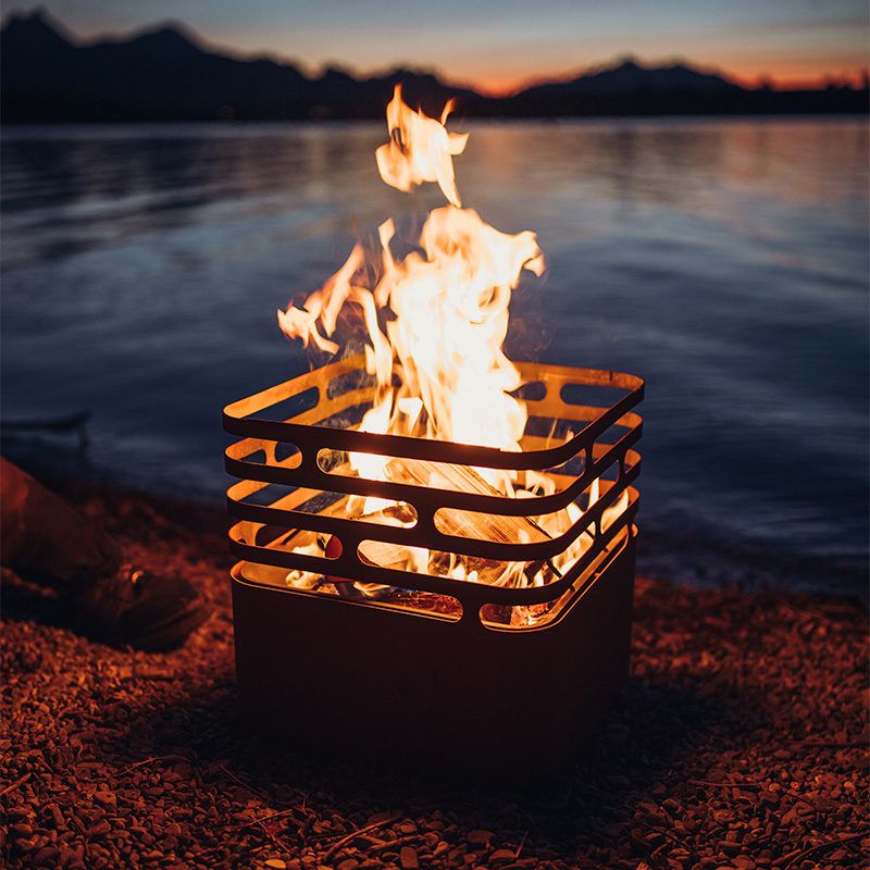 The Cube Firebasket integrates seamlessly into the setting, where a fire pit on the shore of a lake.