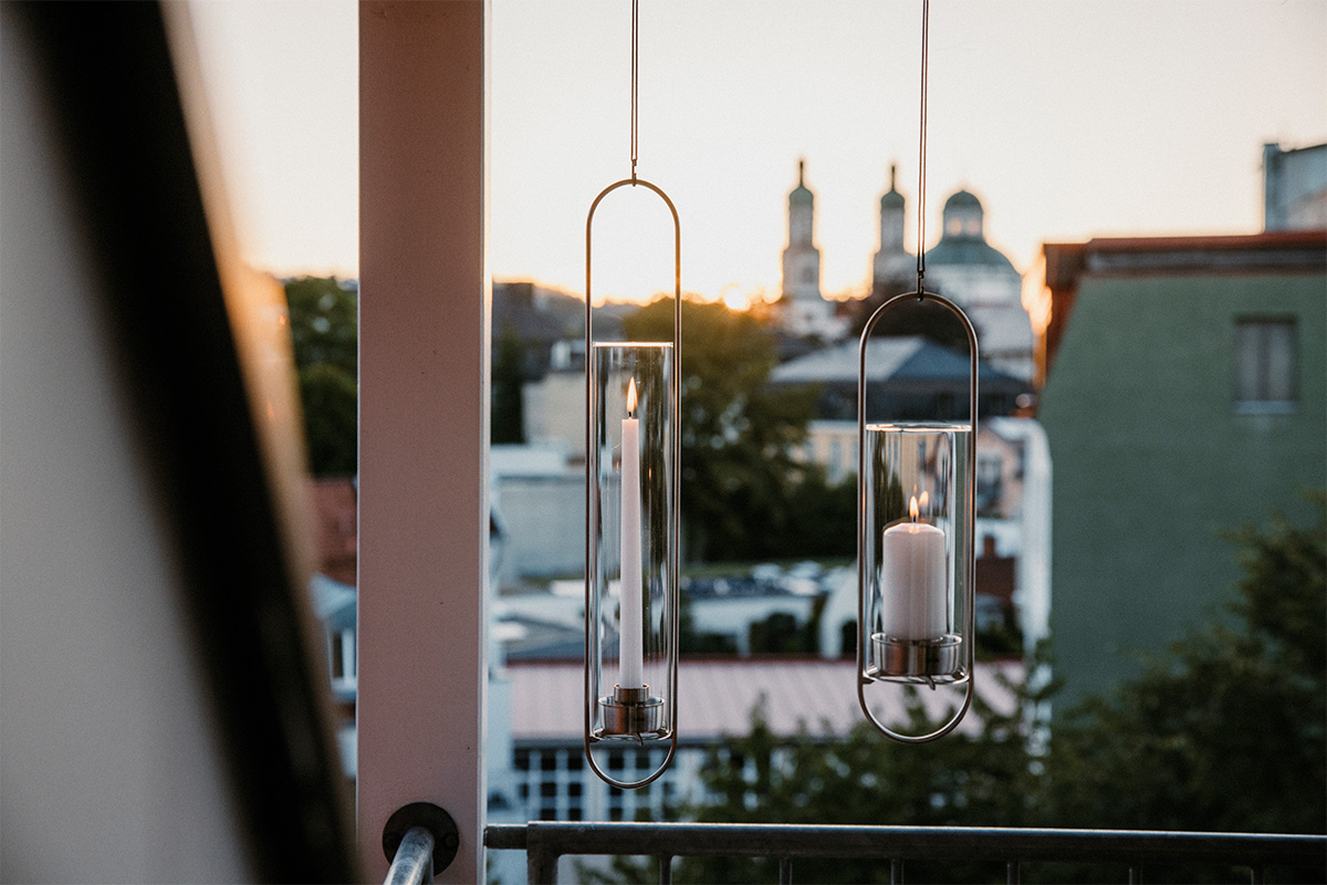 A couple of candles hanging from a metal pole, enriched by the presence of the 00271 Oval Candle, which merges design with utility.