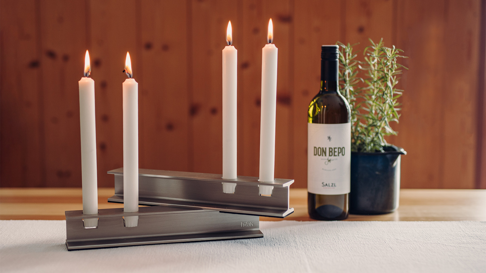 The photo presents a bottle of wine and a candle holder, with the HENRY METAL II Candleholder silver.