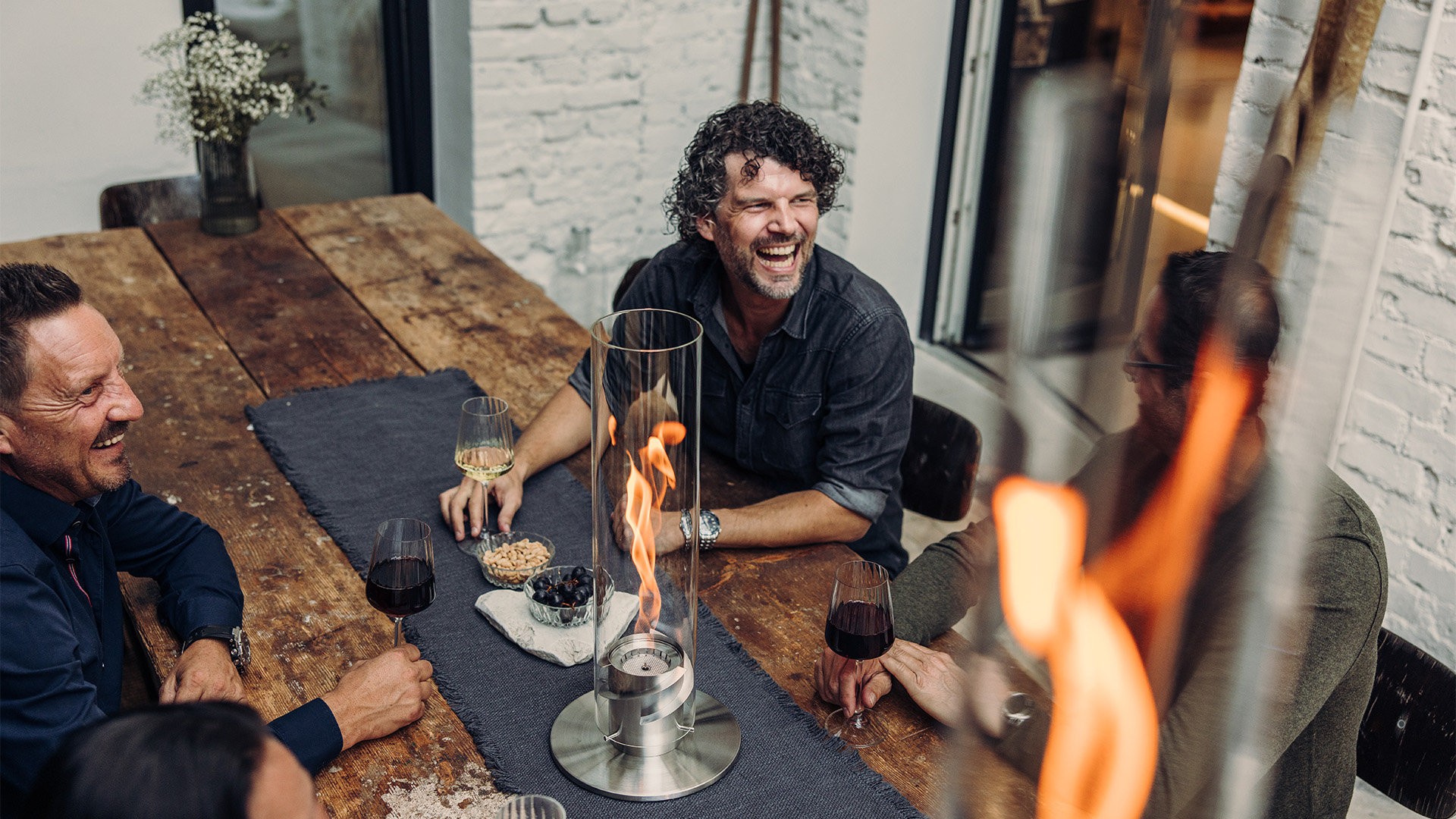 Experience a group of people sitting around a table with the refined touch of the 00695 Spin 1200 Tablefire silver.