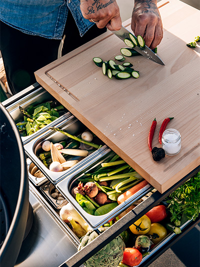 Depicted here is a man cutting vegetables, with the FIRE KITCHEN.