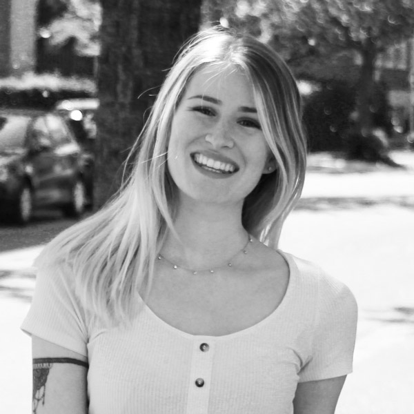 a woman with tattoos standing in front of a building.