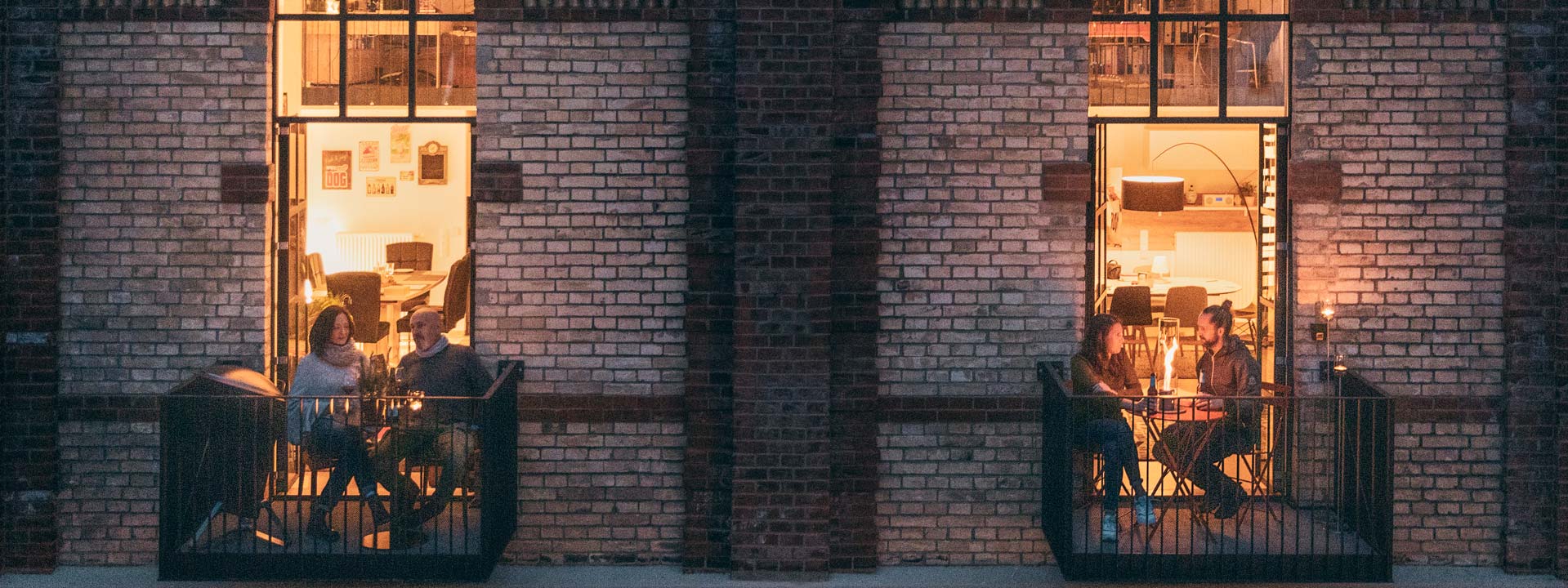 The photo presents people sit on the balcony of a building at night, with the LOGO SPIN Table-top fireplace.