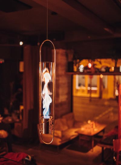 A view of a light hanging from the ceiling in a restaurant, with the SPIN 1200 Base silver.