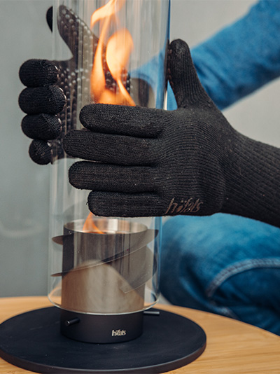 Scene showing a person wearing the aramid gloves, touching the hot surface of a burning tablefire glasscylinder