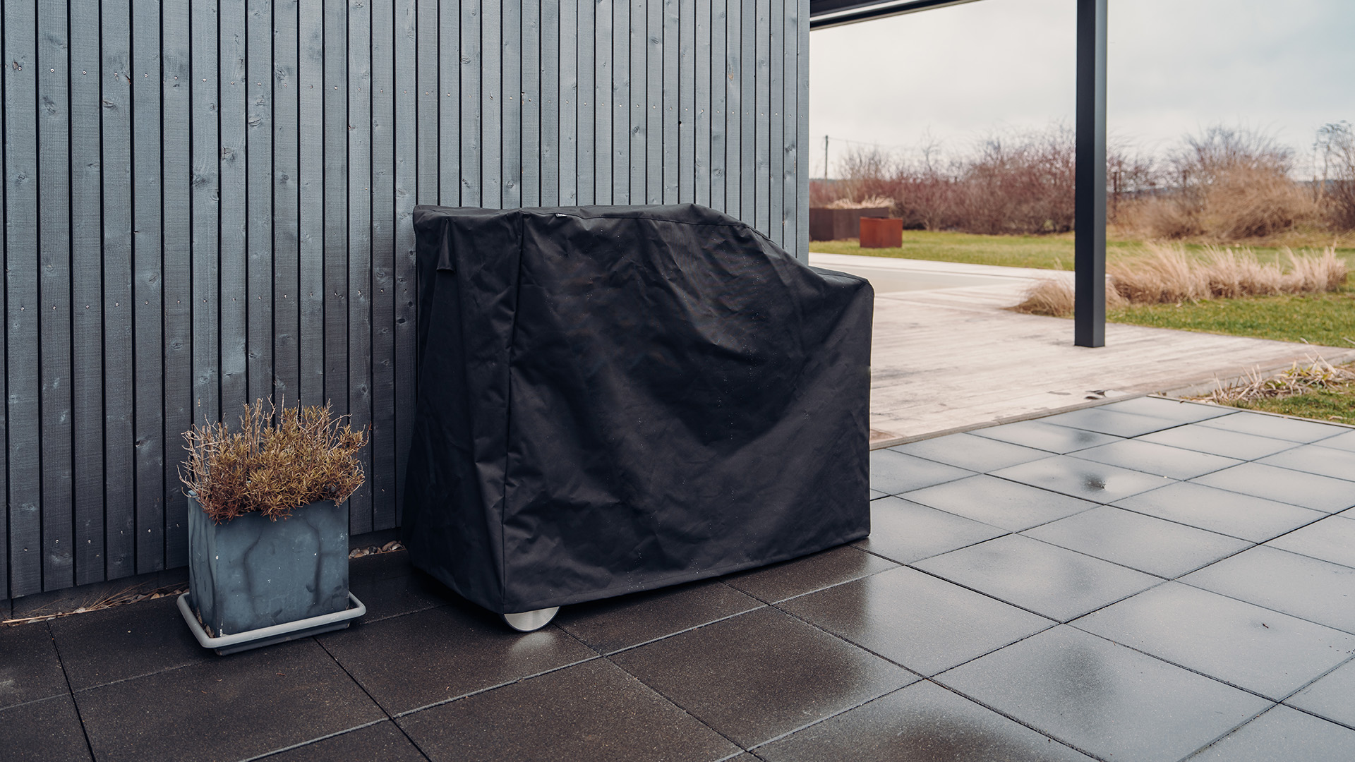 The 00826 Fire Kitchen Cover 57 integrates seamlessly into the setting, where a black predective cover is sitting on the ground.