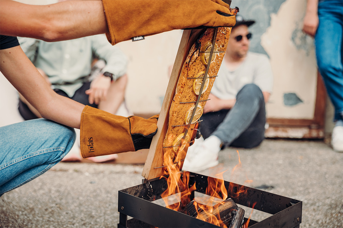 Flame-grilled salmon board A view of a man is putting a fire in a fire pit, with the Flame-grilled salmon board.