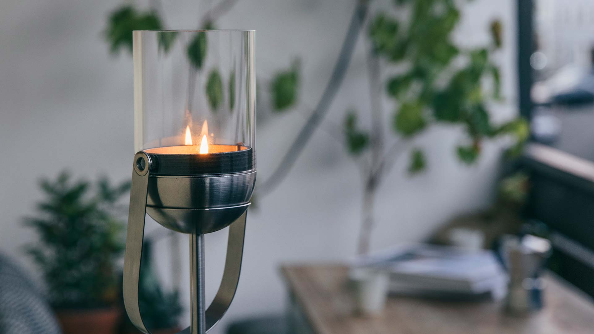 A view of a candle is lit in a glass holder, with the GRAVITY CANDLE Base.