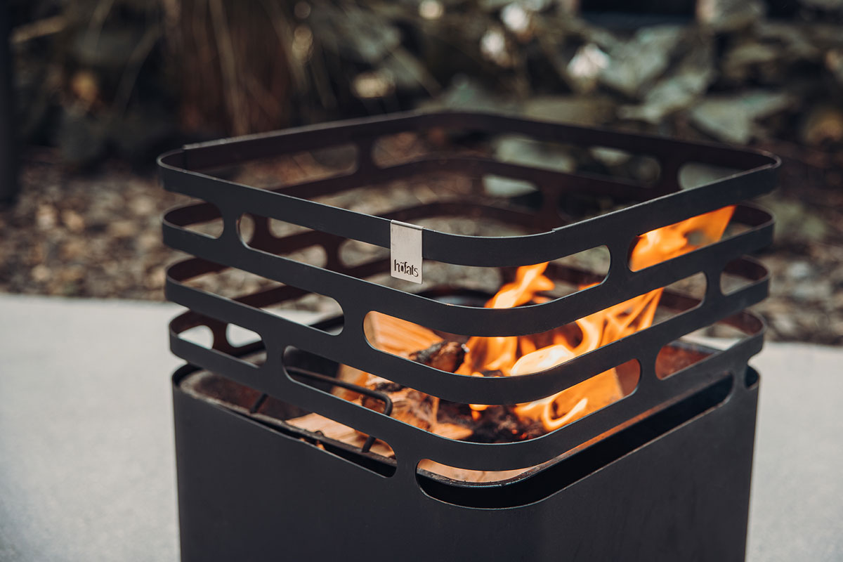 The Cube Firebasket black integrates seamlessly into the setting, where a fire pit with a fire inside of it.