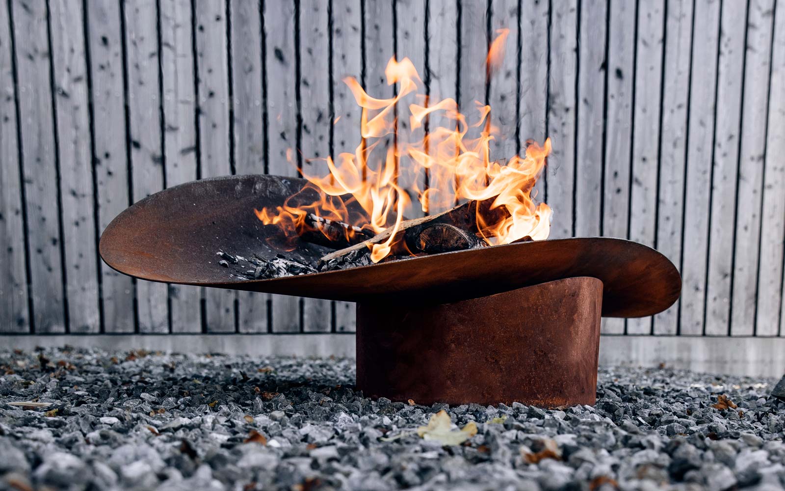 This image shows a fire pit with a fire in it, with the ELLIPSE Fire Bowl.