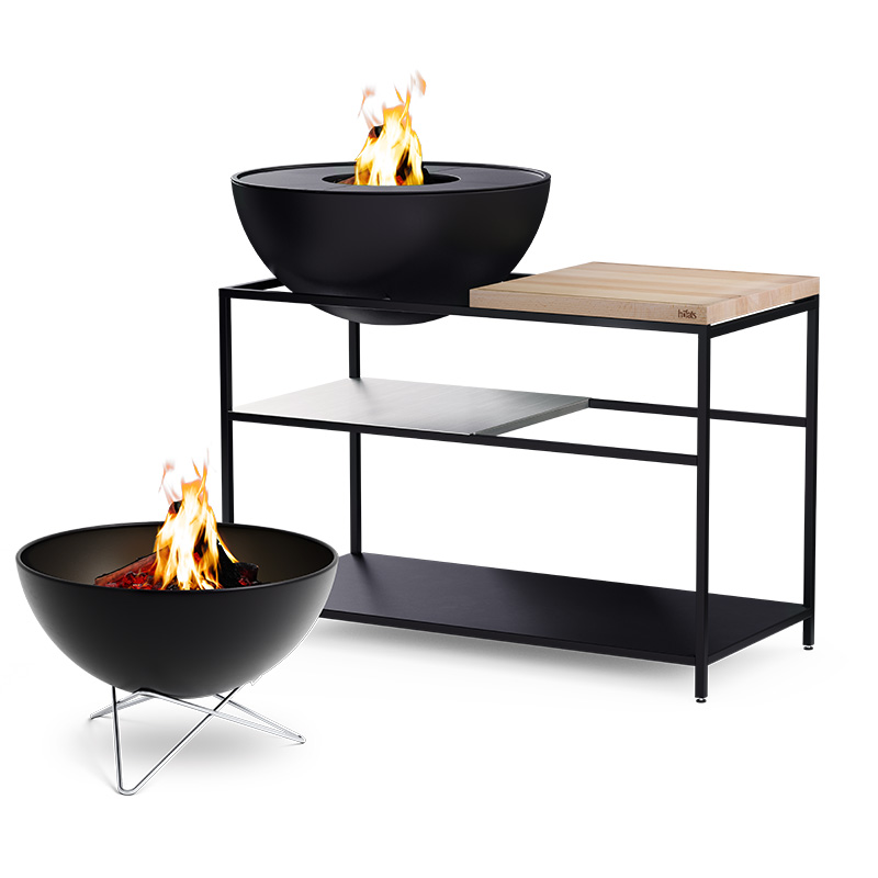 FIRE KITCHEN with BOWL 70 Plancha BBQ Set low The photo presents a fire pit and a table with a fire, with the FIRE KITCHEN with BOWL 70 Plancha BBQ Set incl. wheels.