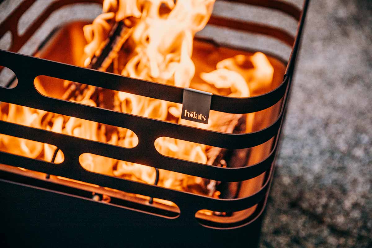 How to Start a Fire A fire pit with a metal grill in the middle the Cube Firebasket black complements the moment with its thoughtful design.