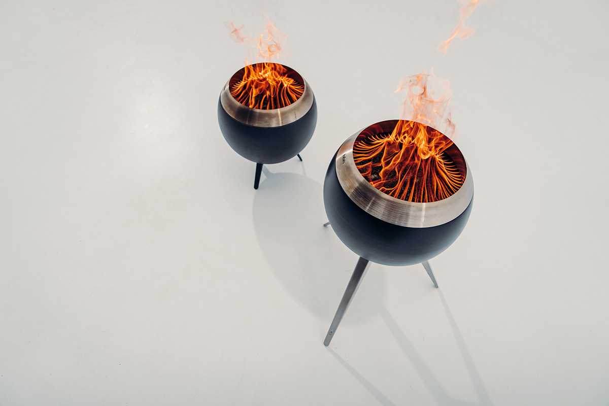 Two fire pits on a white surface, enriched by the presence of the 00717 Moon 45 with high stand, which merges design with utility.