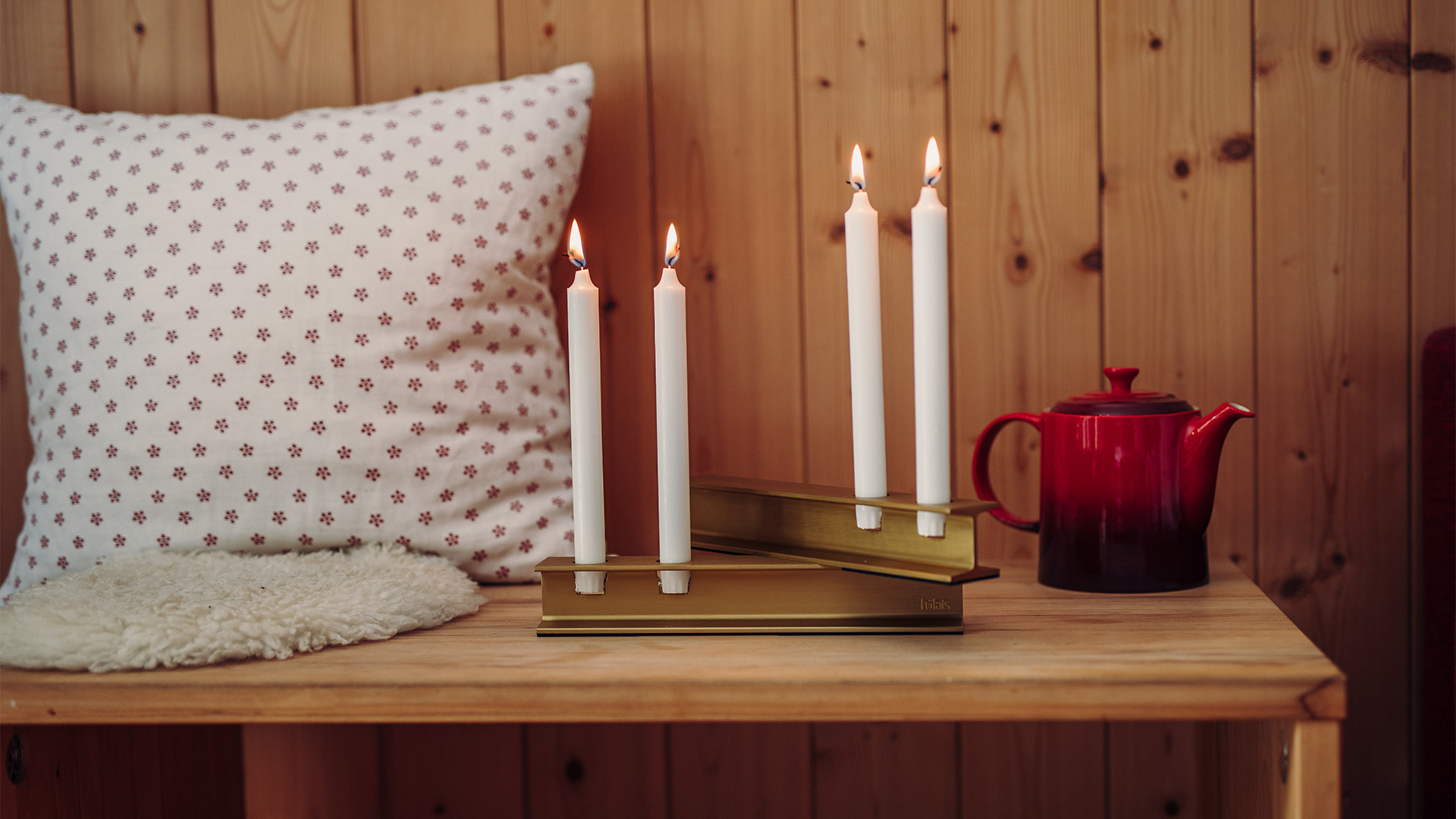 A depiction of a table with a candle, a book and a mug, featuring the 00662 Henry Metal II Gold as a central and purposeful element.