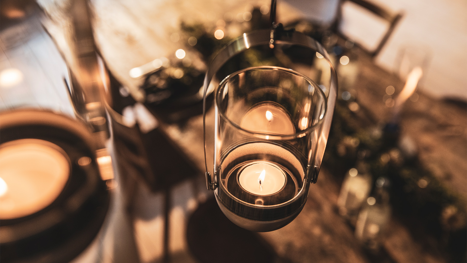 Two candles are lit on a table, enriched by the presence of the Gravity Candle Hanging System, which merges design with utility.