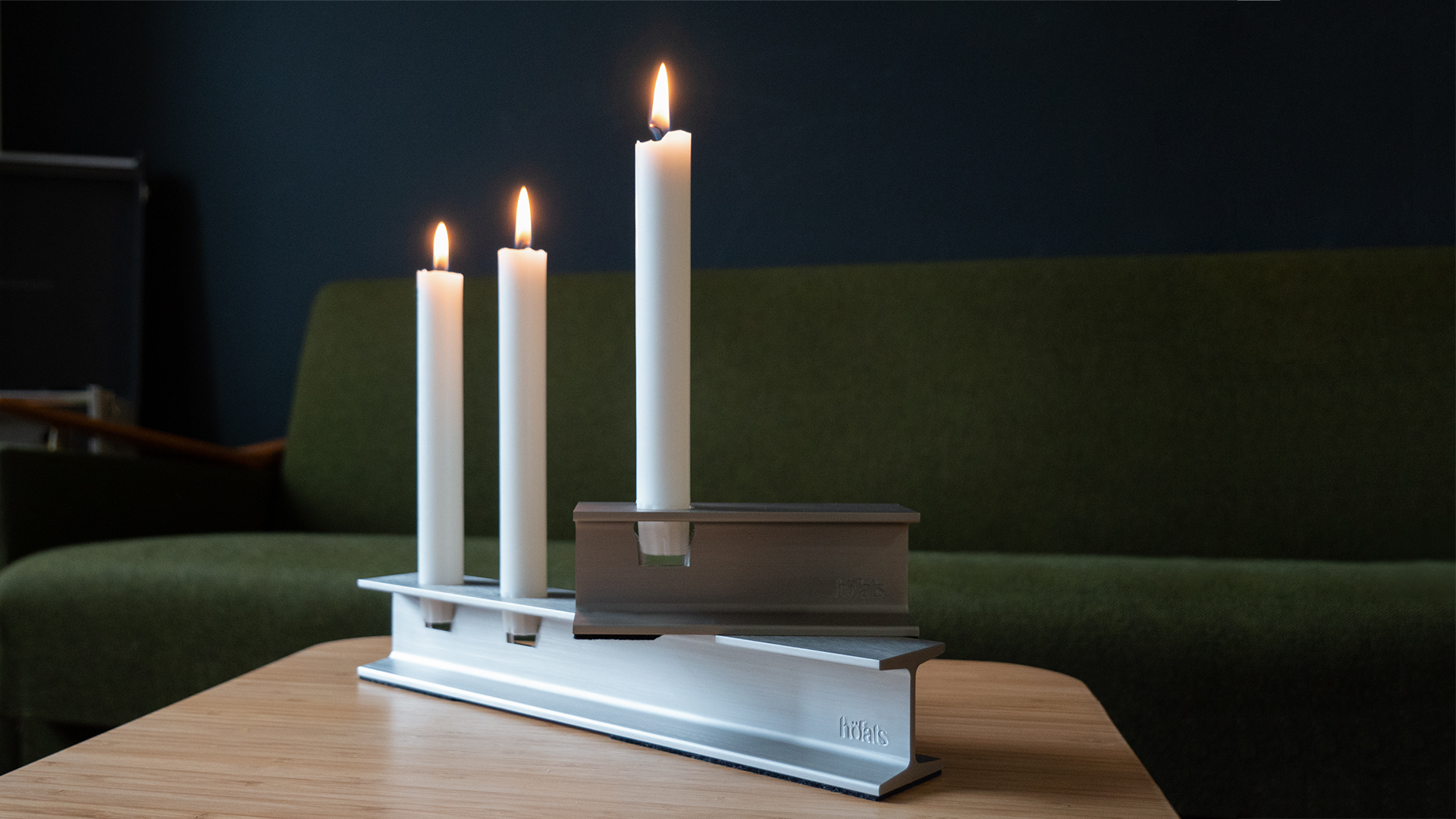 The 00798 Henry Metal I silver is shown as a white candle on a table with a green couch, creating a stylish and accessible visual.