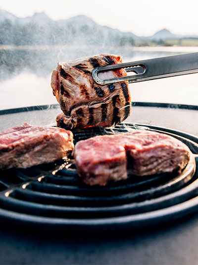 a person is grilling meat on a grill.