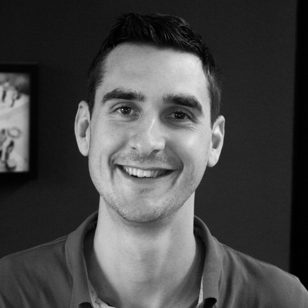 a man smiling in a black and white photo.