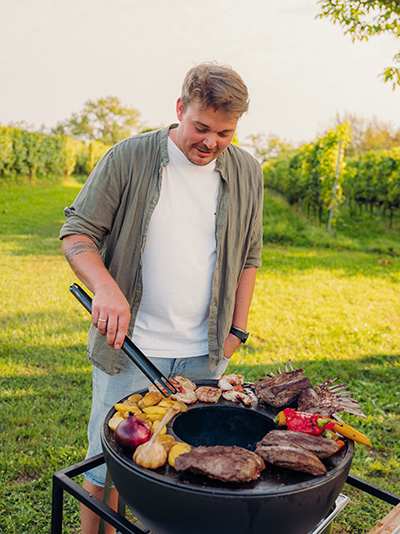 A man cooking food on a grill, with the Bbq Tools Tong adding a functional and elegant touch to the scene.