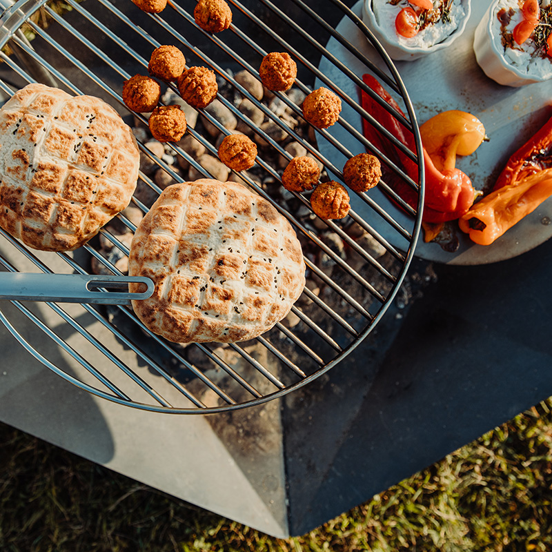 Scene showing a grill with food on it, where the Triple Fireplace stands out for its practical elegance.