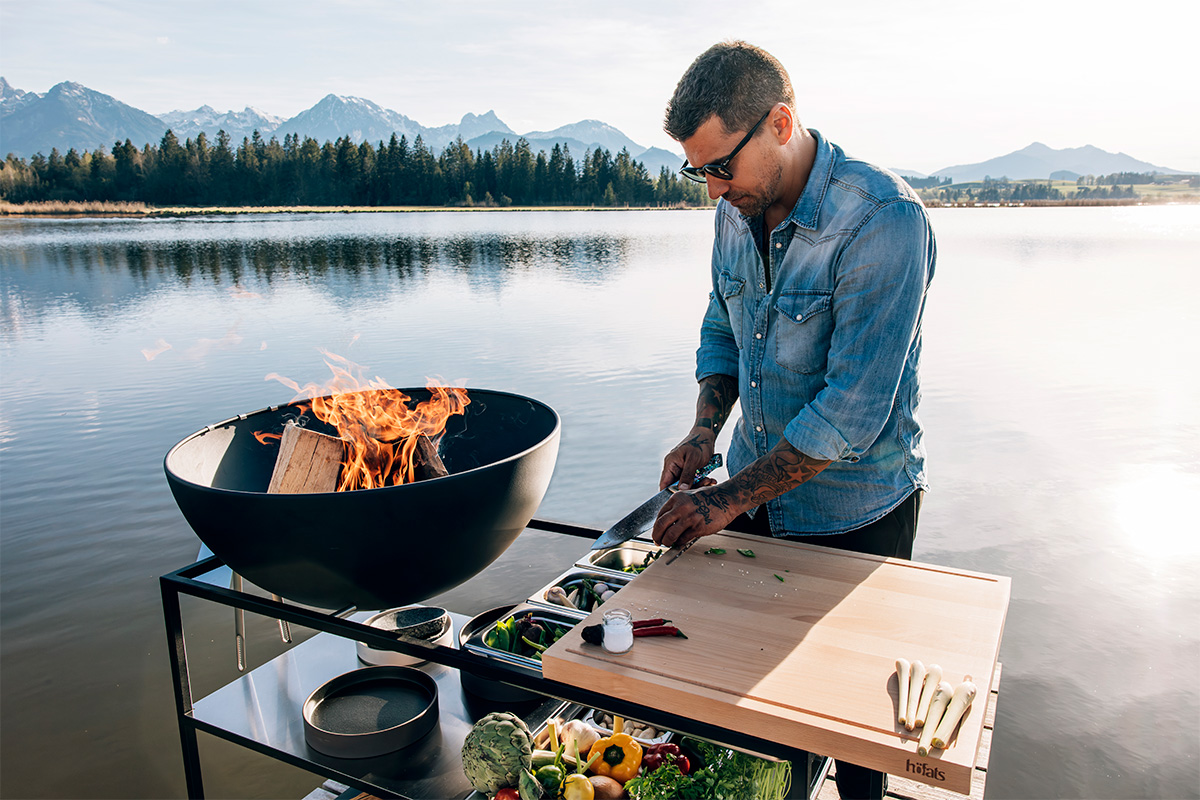A man cooking on a grill, with the 00614 Fire Kitchen Worktop adding a functional and elegant touch to the scene.