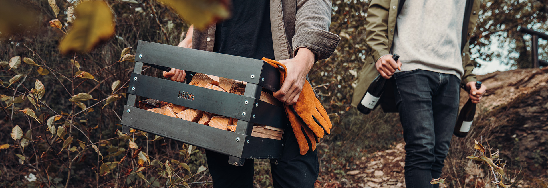 Illustrated is a man carrying a suitcase with a woman walking behind, with the CRATE Fire Basket.