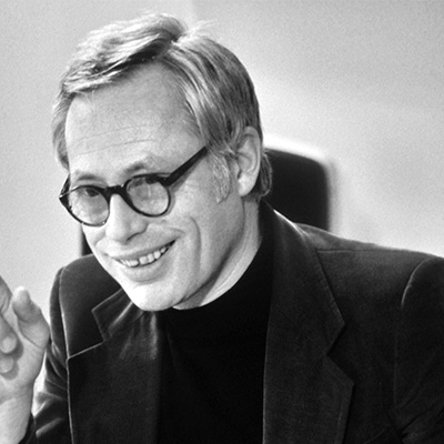a man in a suit and glasses sitting at a table
