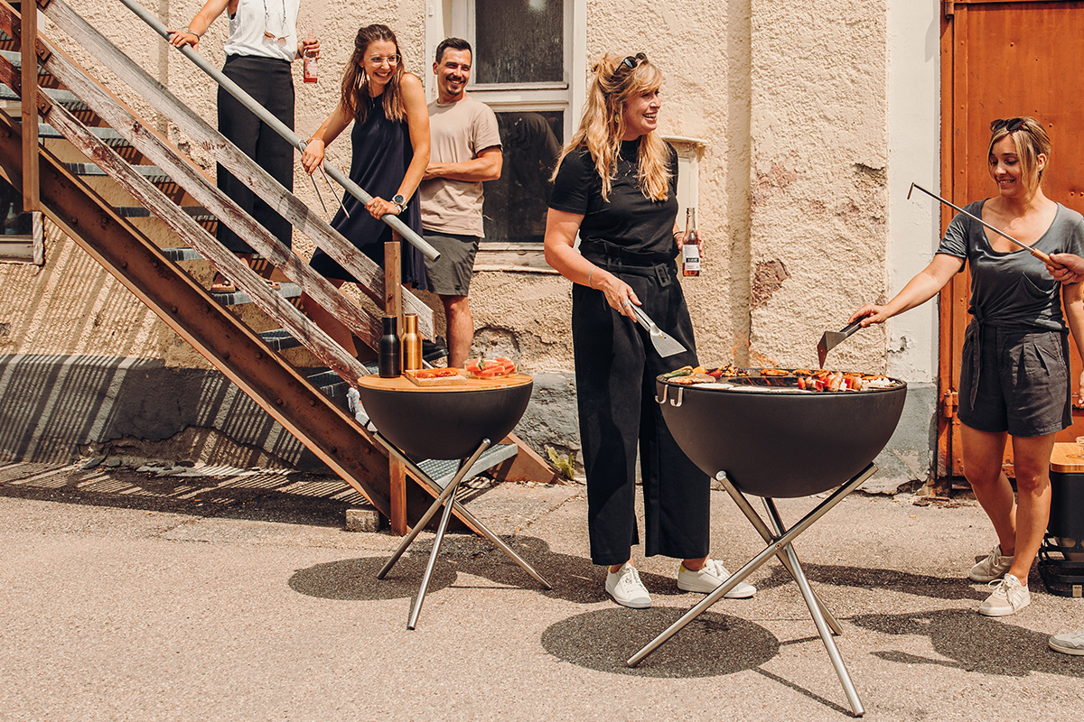 Depicted here is a group of people standing around a grill, with the BOWL 57 Board.