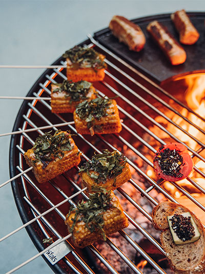 A view of a grill with meat and vegetables on it, with the BOWL Grid.