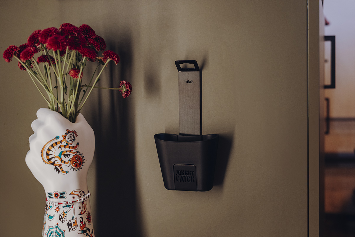 The 00842 Johnny Catch Cup Black Bottleopener integrates seamlessly into the setting, showing a vase in the form of a hand with flowers