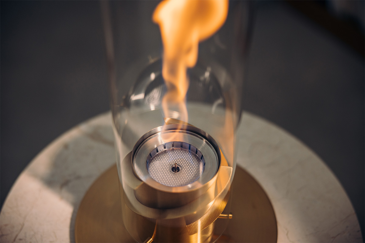 The 00699 Spin 1200 Tablefire Gold is shown as a glass cylinder with a flame inside, creating a stylish and accessible visual.