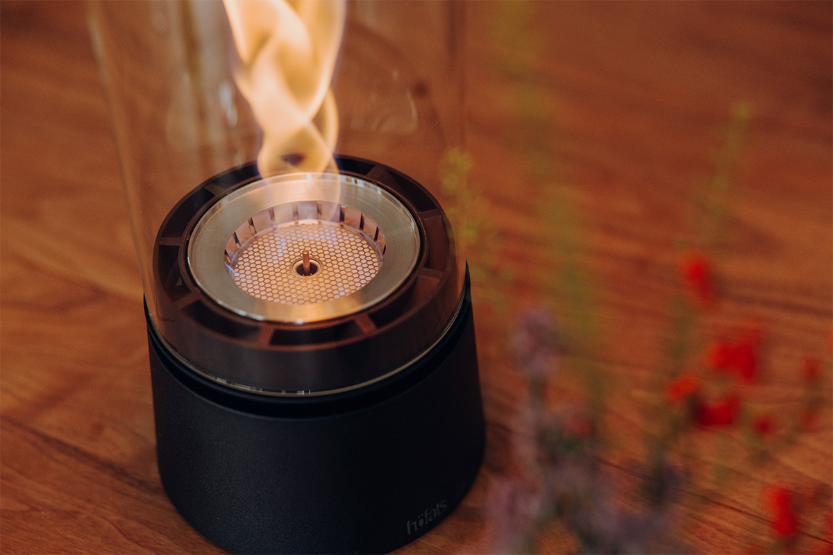 SPIN air 1200 Tabletop Fireplace matte black SPIN air 1200 und 900 mattschwarz auf einem Küchentisch mit vier Personen welche mit einem Rotwein anstoßen close-up