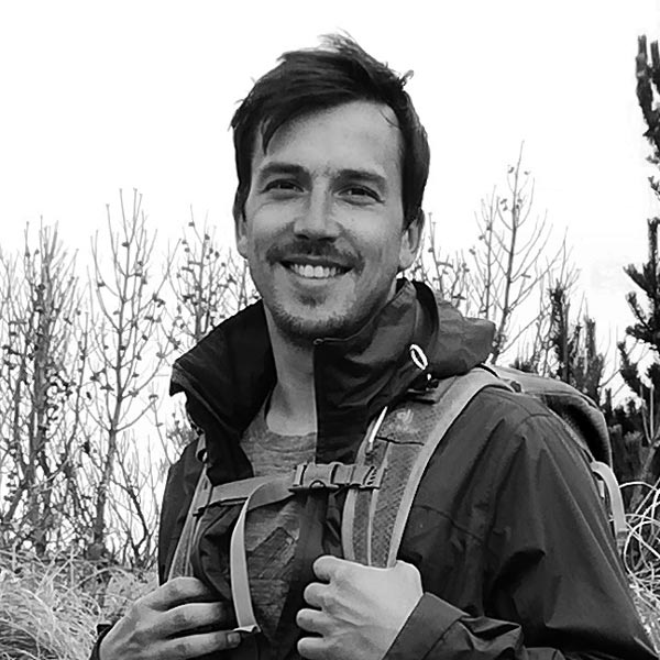 a man in a field with a backpack.