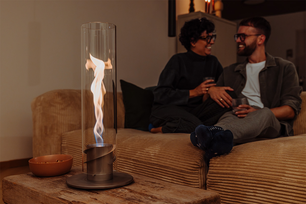 SPIN 1200 Tabletop Fireplace grey The 00697 Spin 1200 Tablefire grey is shown as a man and woman sitting on a couch, creating a stylish and accessible visual.