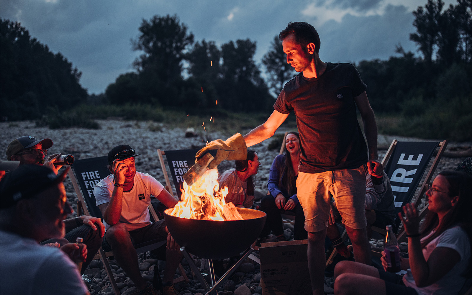 An image showing a group of people sitting around a fire pit, with the SHIRT (Matrix - Parent).