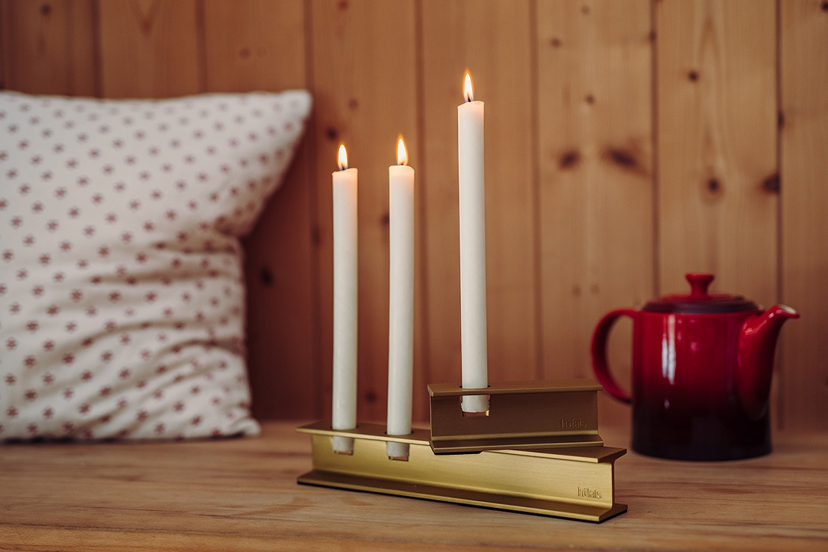 Depicted here is a candle on a table, with the HENRY METAL I Candleholder gold.
