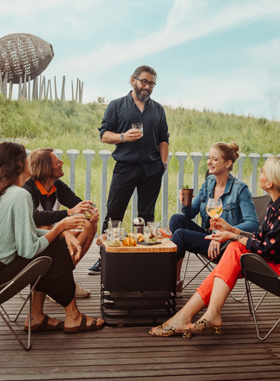 The Cube Firebasket integrates seamlessly into the setting, where a group of people sitting around a fire pit.