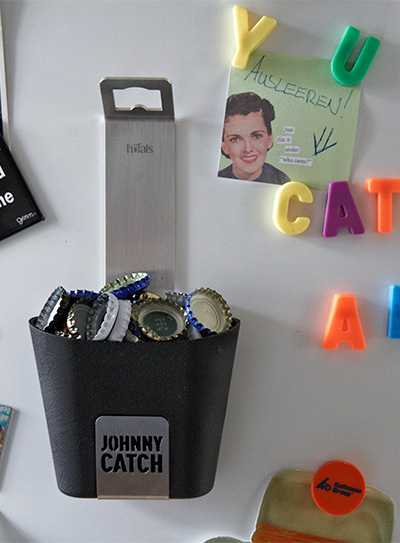 Illustrated is a white refrigerator with magnets and magnets on it, with the JOHNNY CATCH Cup.