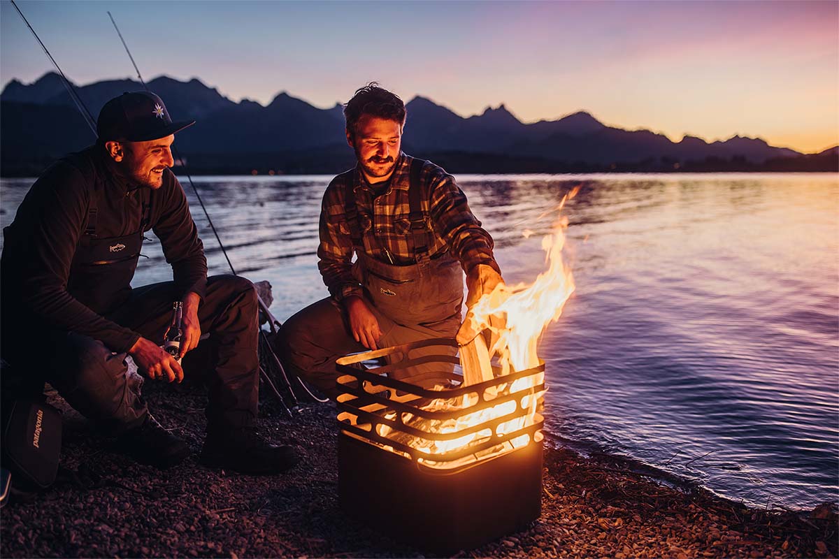 CUBE Fire Basket Corten Steel Two men sitting around a campfire, enriched by the presence of the Cube Firebasket rusty, which merges design with utility.