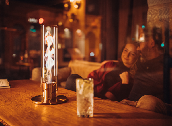 Warmth that gets under your skin A man sitting at a table with a woman, enjoying the warmth of the SPIN Tablefire