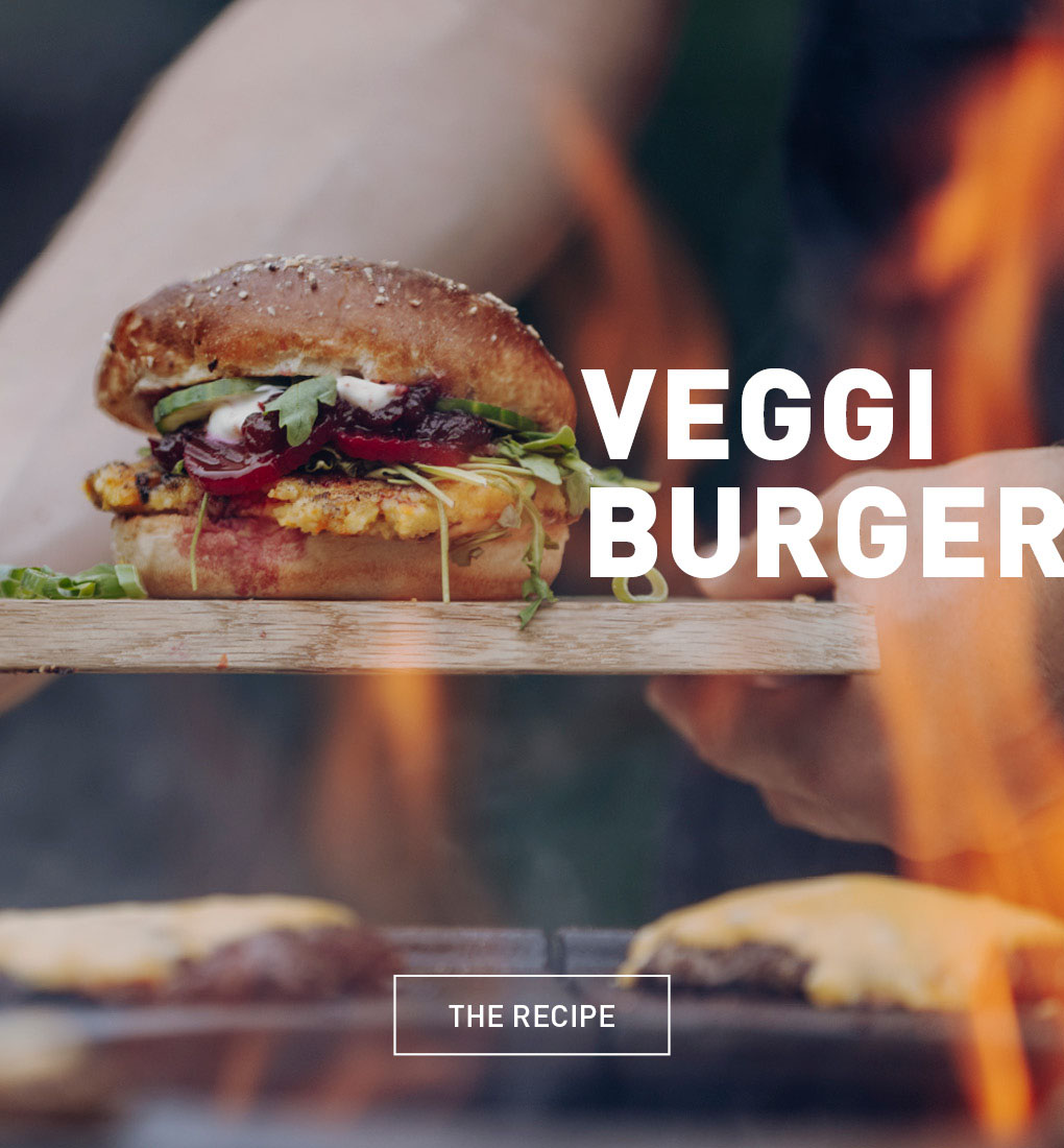 a person holding a hamburger on a grill.