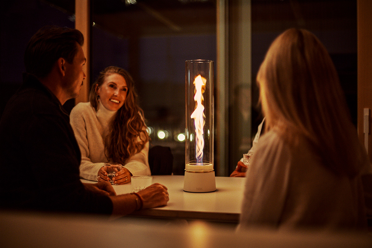Drei Personen sitzen an einem Tisch um SPIN air 1200 creme und unterhalten sich im Licht der Flamme.