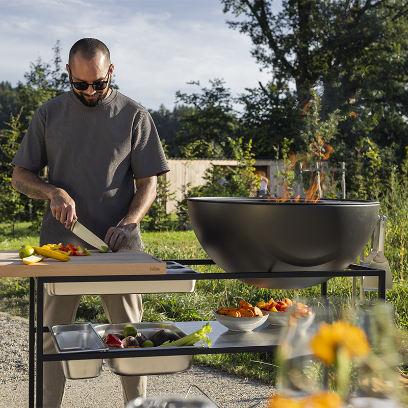 A man preparing food, with the Fire Kitchen adding a functional and elegant touch to the scene.